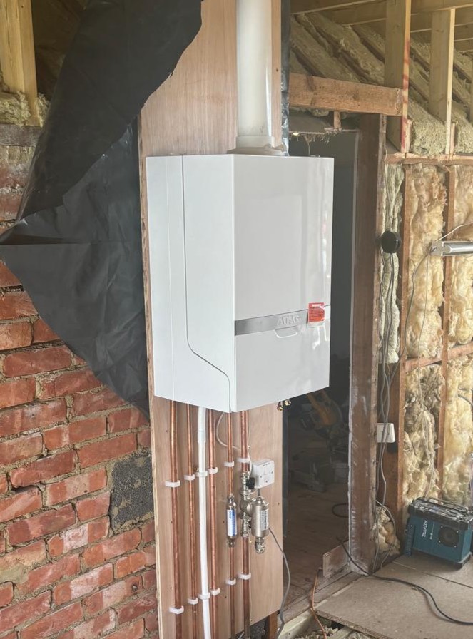 New boiler fitted during a loft conversion with exposed brick and new pipework